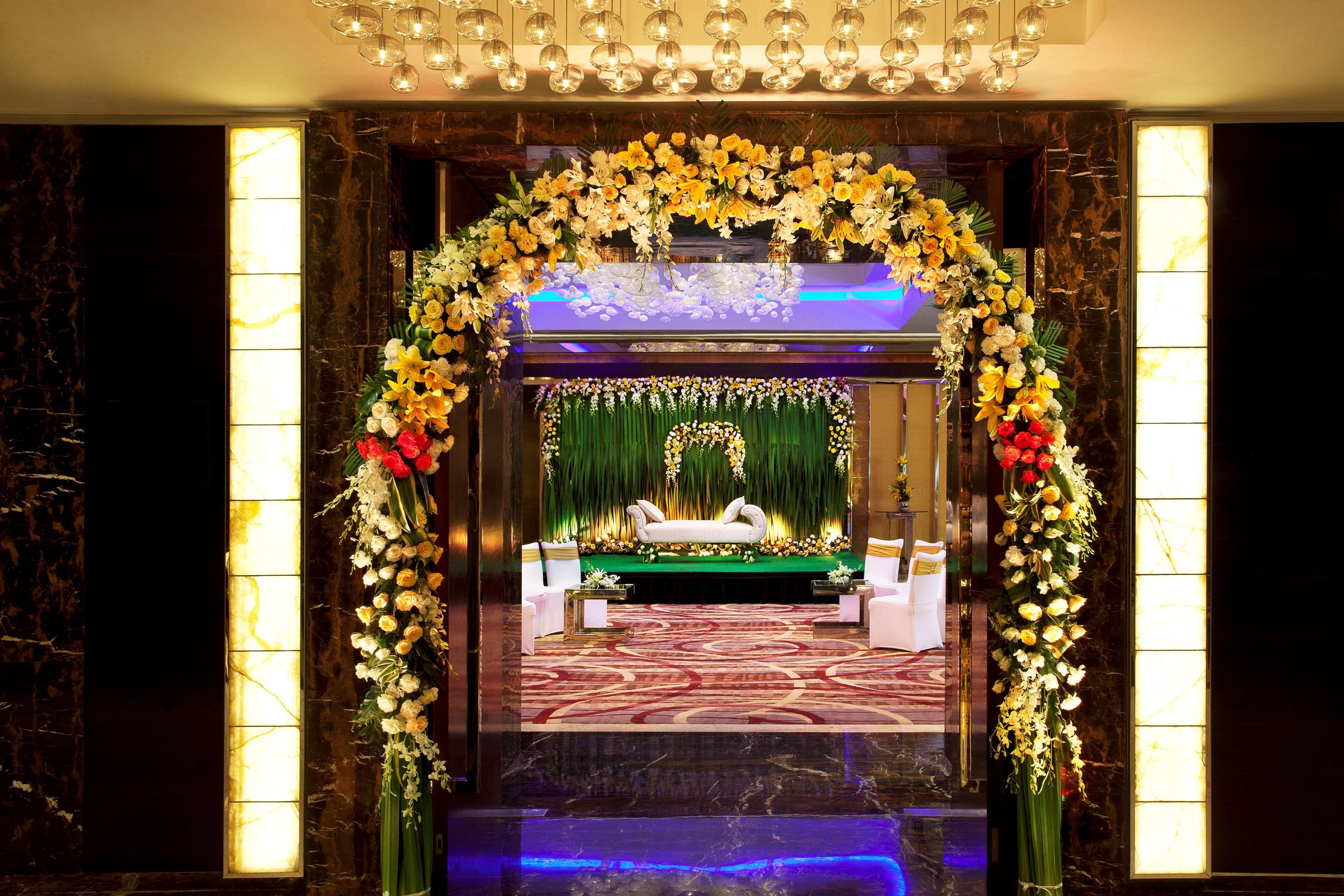 Hotel Radisson Blu Plaza Delhi Airport Nuova Delhi Esterno foto The photo depicts an elegantly decorated entrance with a floral archway. The arch is adorned with a variety of vibrant flowers, adding a touch of color and sophistication. Beyond the arch, there is an interior space that appears to be a luxurious set