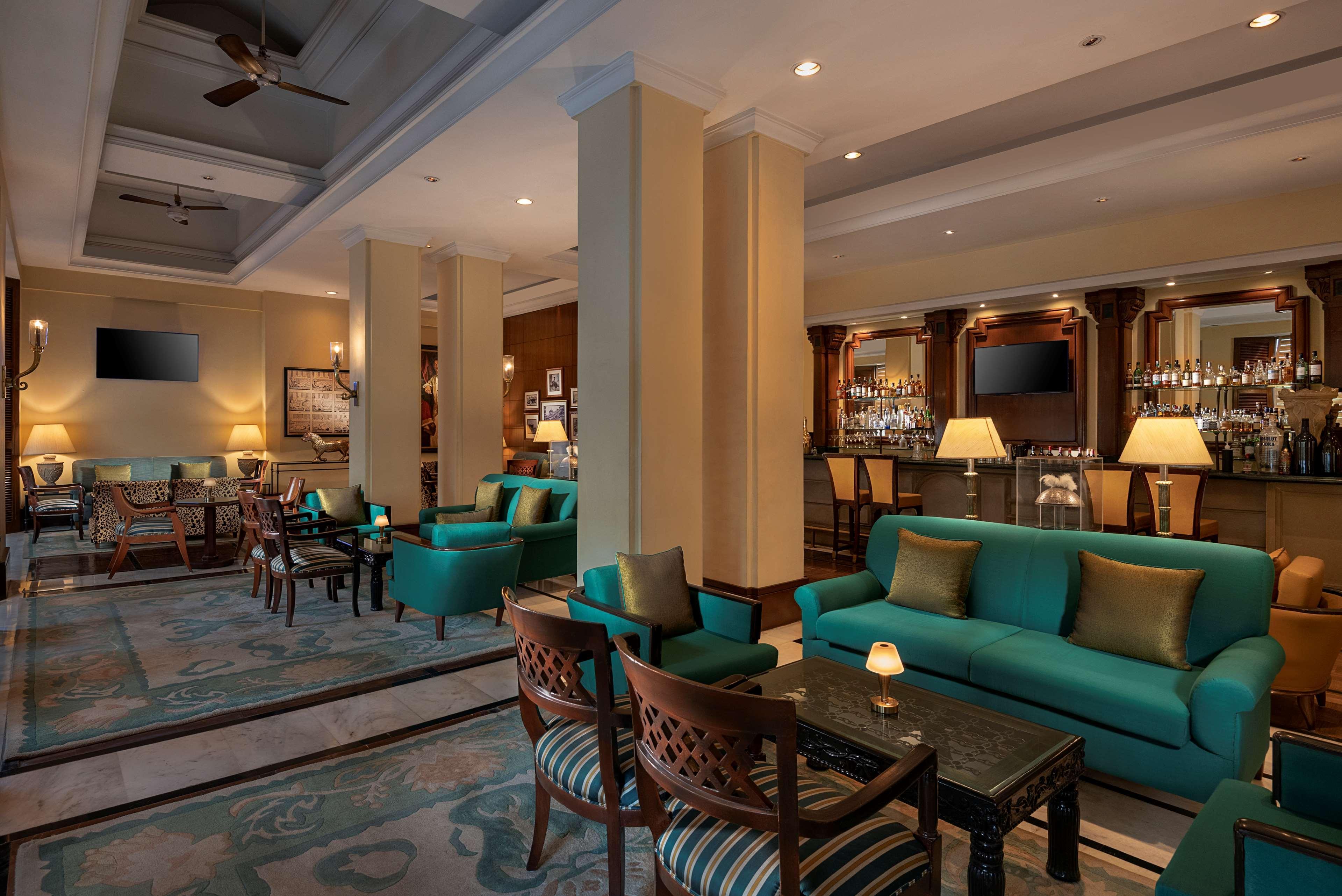 Hotel Radisson Blu Plaza Delhi Airport Nuova Delhi Esterno foto The photo depicts a stylish, upscale lounge or seating area. It features turquoise sofas and chairs arranged around small tables on a patterned carpet. The space is well-lit with ambient lighting and has a modern yet elegant design. In the background