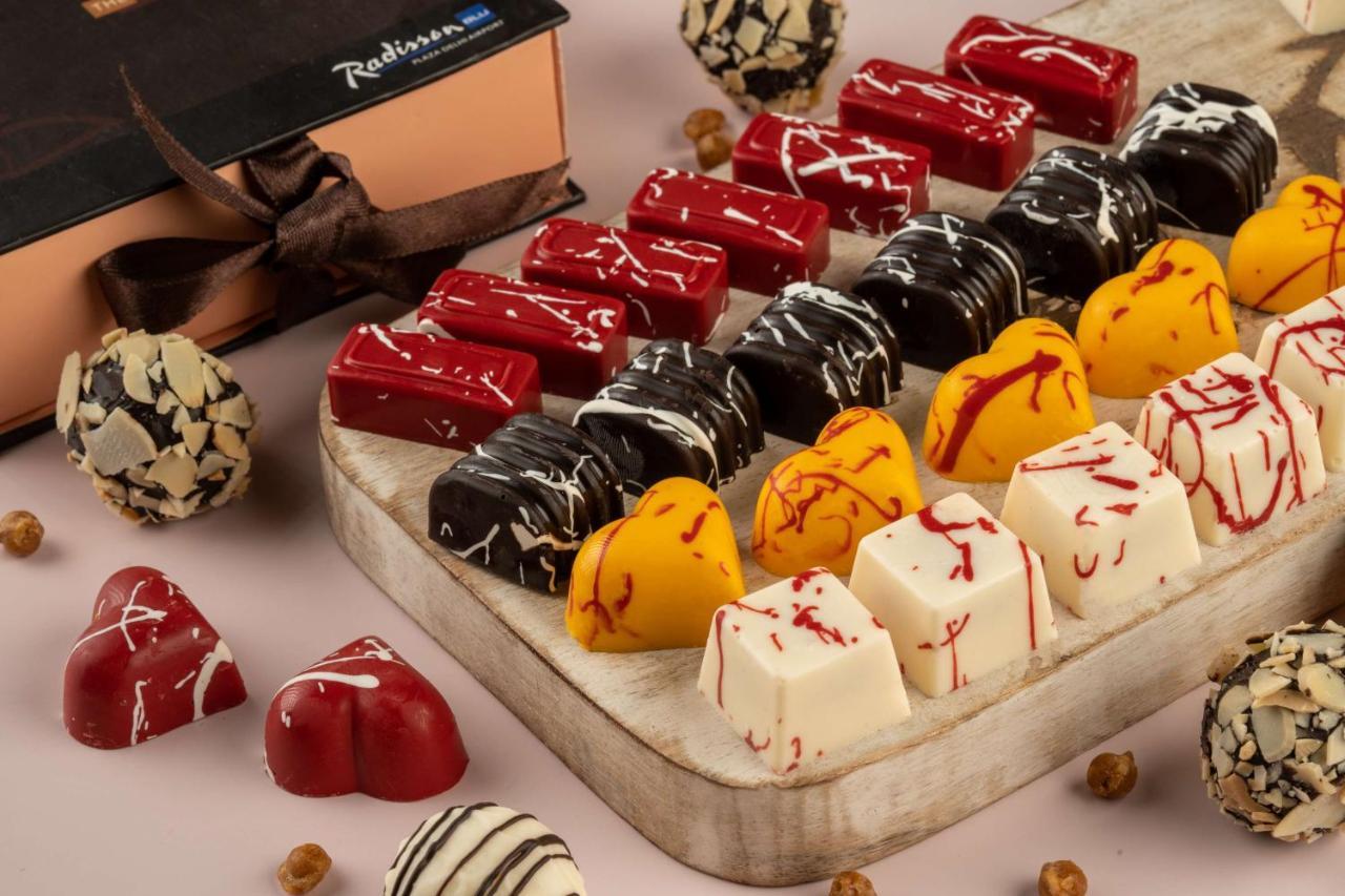 Hotel Radisson Blu Plaza Delhi Airport Nuova Delhi Esterno foto The photo showcases an elegant arrangement of assorted chocolates. There are various shapes and colors, including heart-shaped chocolates in red, white, and yellow, as well as glossy dark chocolates. Some chocolates have decorative swirls or drizzles