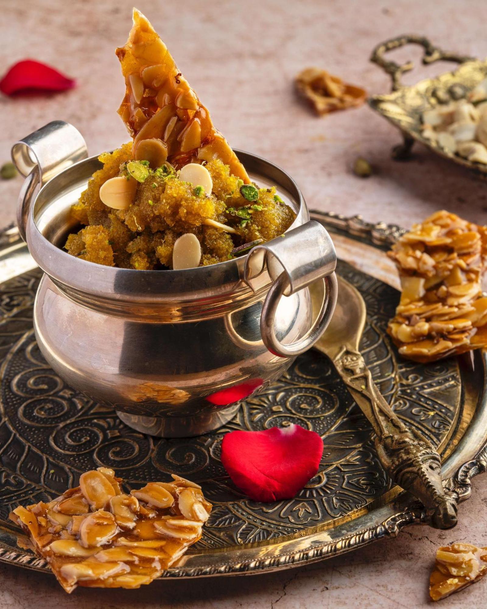 Hotel Radisson Blu Plaza Delhi Airport Nuova Delhi Esterno foto The photo features a traditional Indian sweet dish served in a silver bowl. The dish appears to be a mix of ingredients, possibly made from semolina or lentils, and is garnished with slivers of almonds and pistachios. Next to the bowl is a decorative