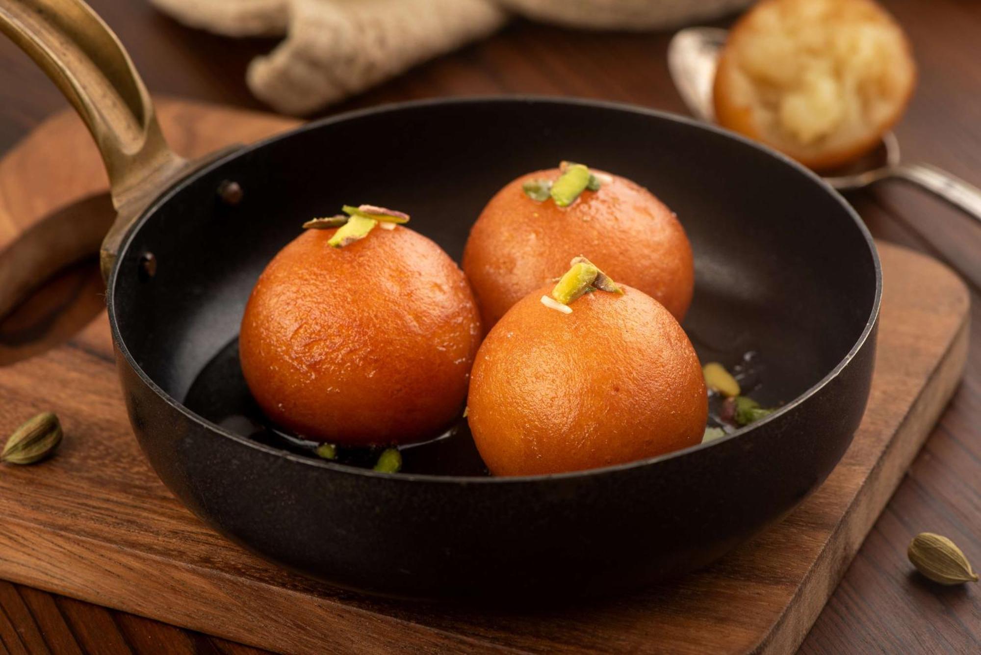 Hotel Radisson Blu Plaza Delhi Airport Nuova Delhi Esterno foto The photo shows three round, golden-brown sweets sitting in a small black frying pan. These sweets are likely Gulab Jamun, a popular Indian dessert made from milk solids, sugar, and flavored with cardamom and rose water. They are garnished with piece
