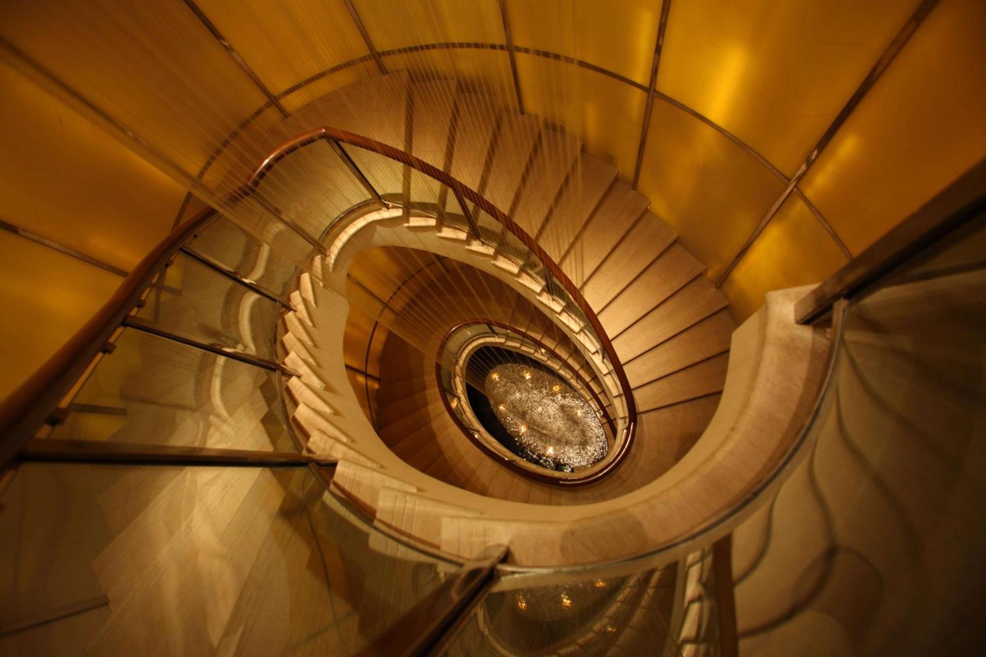 Hotel Radisson Blu Plaza Delhi Airport Nuova Delhi Esterno foto The photo shows a beautifully designed spiral staircase. It features wooden steps that wind around a central column, with glass railings adding a modern touch. The staircase is illuminated with warm lighting, enhancing the elegant and sophisticated a