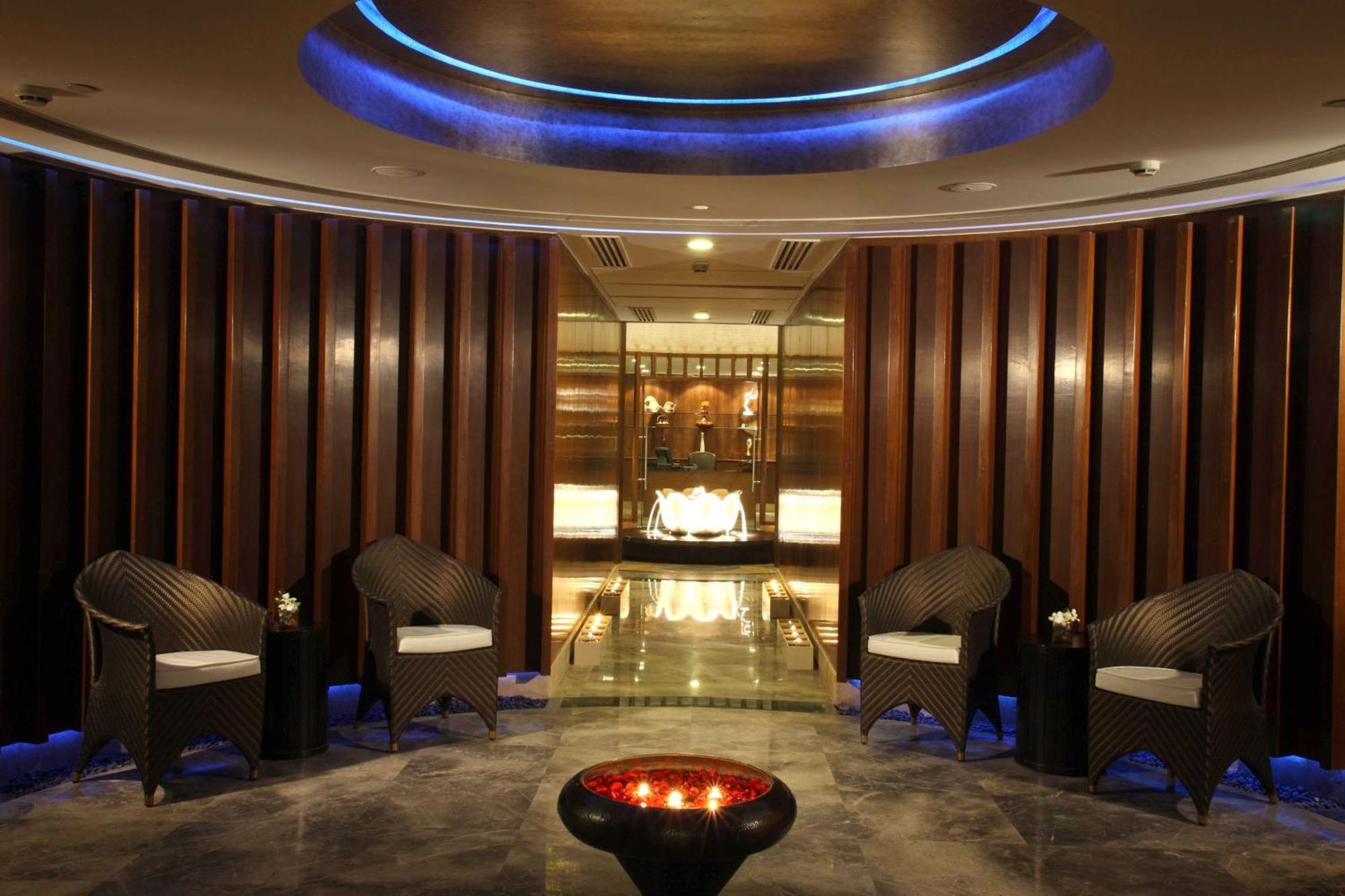 Hotel Radisson Blu Plaza Delhi Airport Nuova Delhi Esterno foto The photo shows an elegant spa or wellness area. It features a modern, tranquil design with a circular ceiling that has blue lighting. In the center, there is a decorative bowl with candles, creating a soothing ambiance. Surrounding the bowl, there a